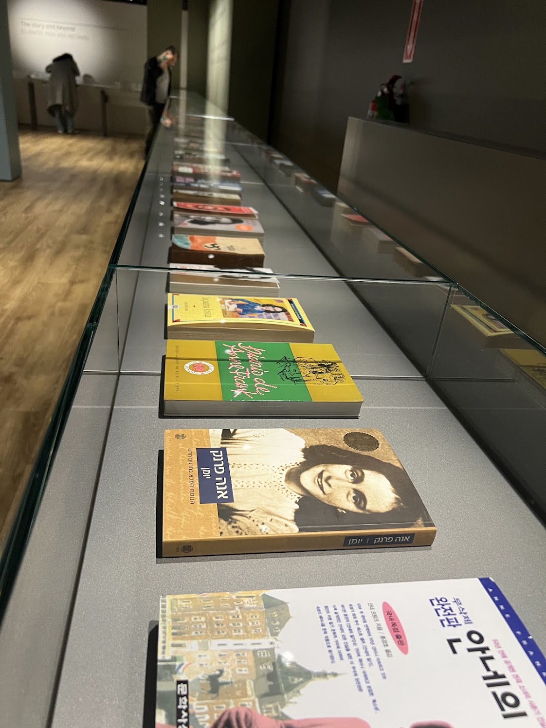 Editions of Anne Frank's diary in multiple languages, including Korean, displayed in a museum case